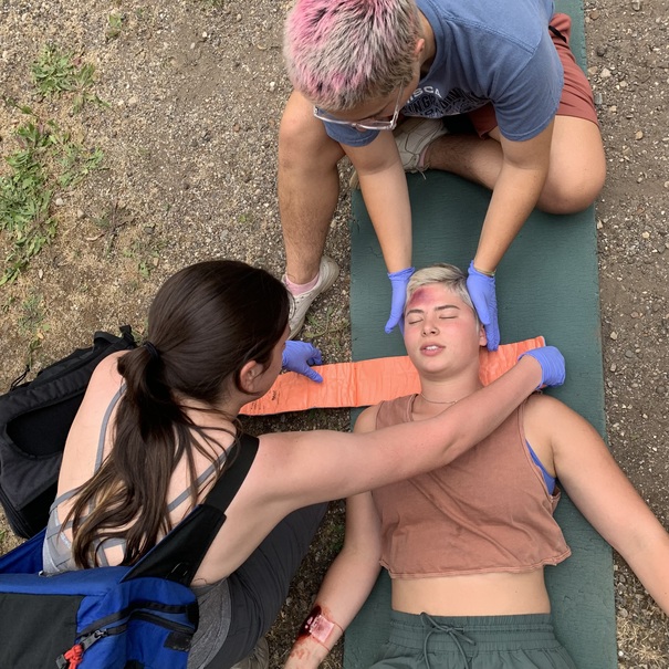 Wilderness Medicine students applying a C-collar for a mock patient with a potential spinal injury